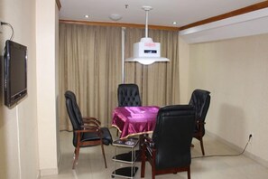 A conference room with a table, four chairs, a television, and a ceiling-mounted light fixture. - Yijing Hotel (Guangzhou)