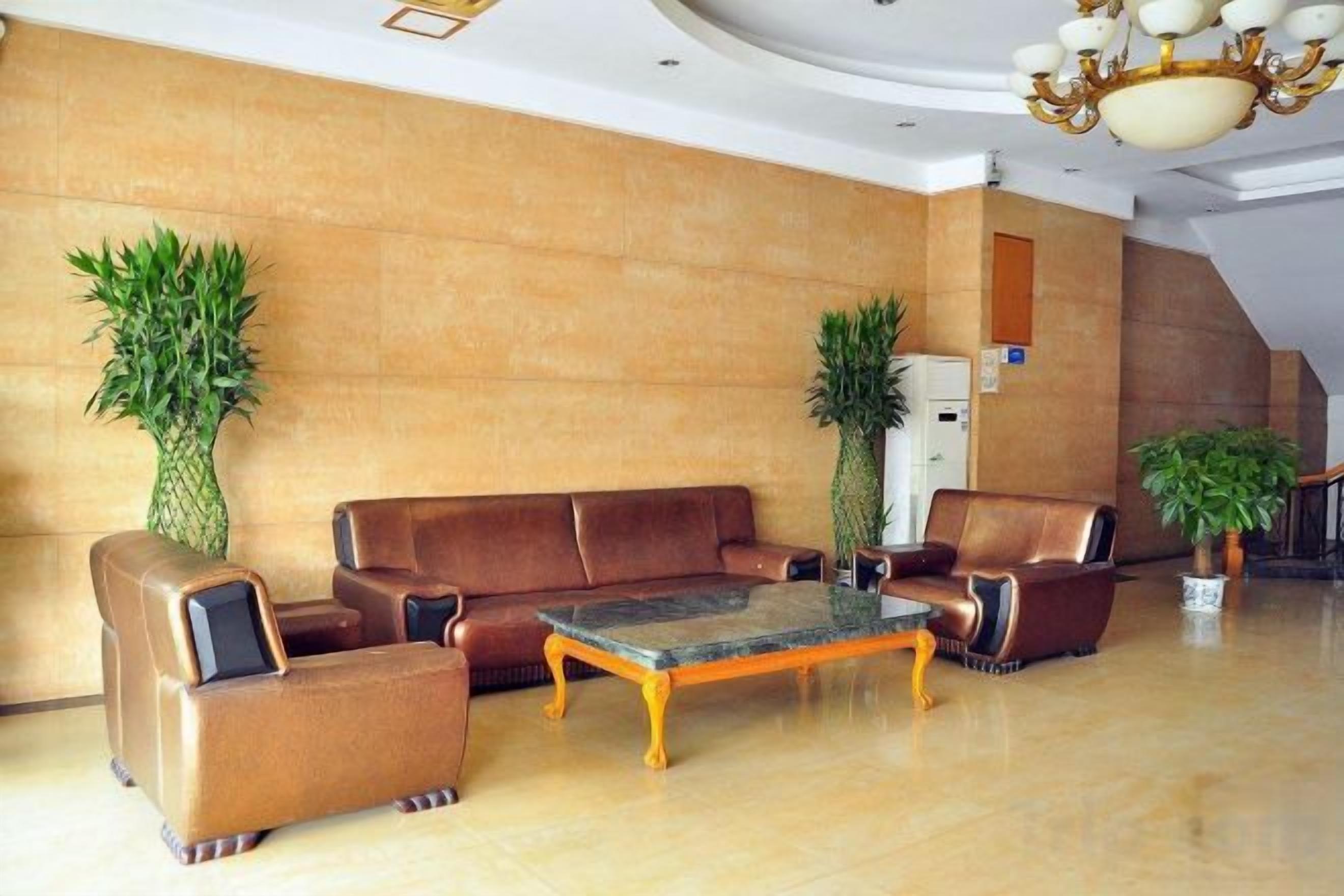 A lobby with leather sofas, a coffee table, and potted plants.