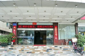 A hotel entrance with a tiled roof, a glass door, and a red sign above the entrance. - Yijing Hotel (Guangzhou)