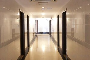 A long, narrow hallway with doors on both sides, leading to a bright room at the end. - Yijing Hotel (Guangzhou)