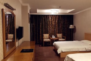 Une chambre d’hôtel comprenant un lit, un bureau, une chaise, une petite table avec une lampe et un grand miroir.