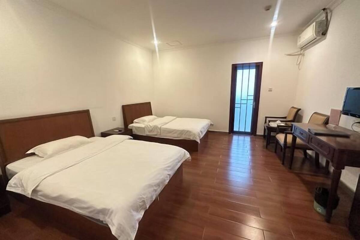 Ein Hotelzimmer mit zwei Betten, einem Schreibtisch, einem Stuhl und einem Fernseher.