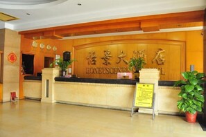 A reception desk with a wooden finish and a sign indicating a hotel name. - Yijing Hotel (Guangzhou)