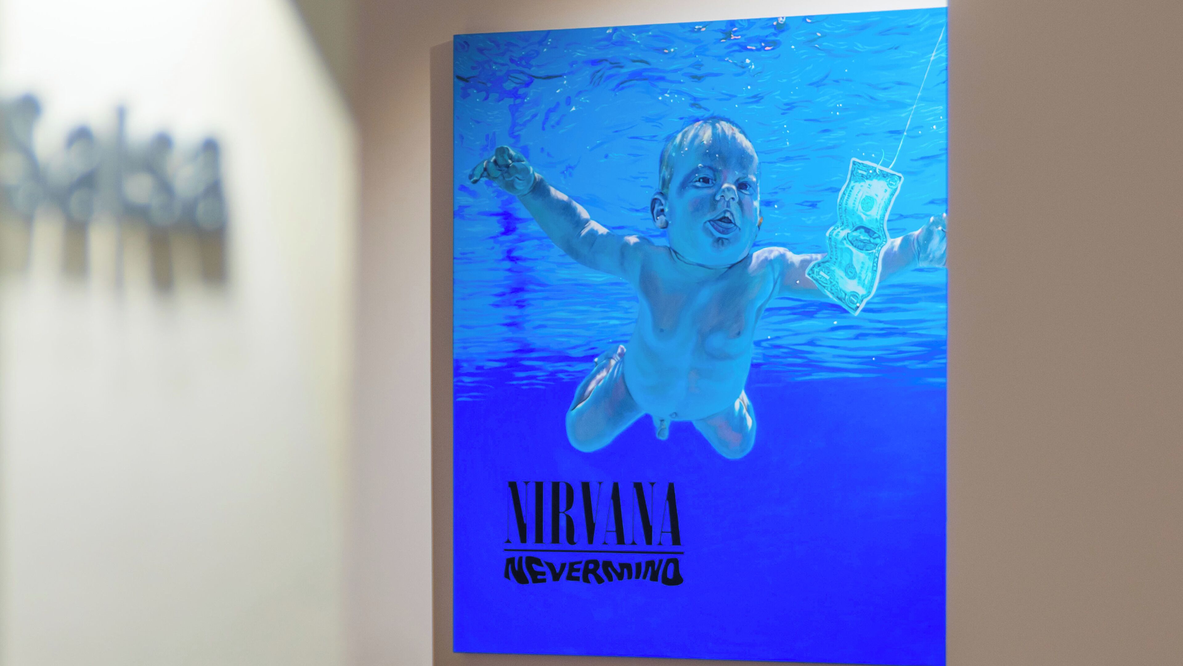 A poster with a child swimming underwater, holding a dollar bill, and the text "NIRVANA NEVERMINO".