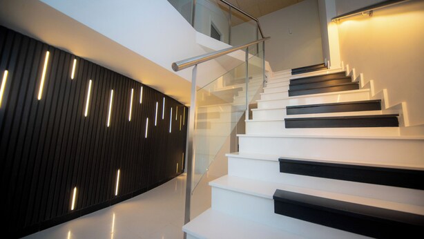 Un escalier moderne avec des rampes en verre et un design épuré.
