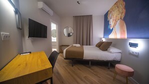 Une chambre d’hôtel avec un lit, un bureau, une chaise, une télévision, un tableau et une fenêtre.