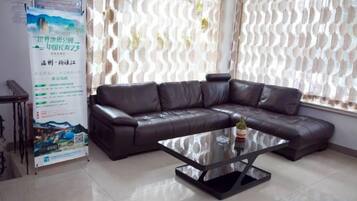 A room with a brown leather sofa, a glass coffee table, and a poster on the wall.