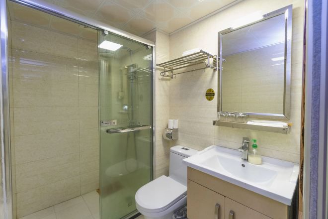 A bathroom with a glass shower enclosure, a toilet, a sink with a mirror, and a towel rack.