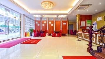 Un vestíbulo de hotel con recepción, zona de estar y escalera.