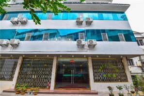 A multi-story building with air conditioning units, large windows, and a patterned entrance. - Jinyuan Motel (Yueqing)