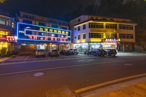 A building with illuminated signage, parked cars, and a street in the foreground. - Jinyuan Motel (Yueqing)