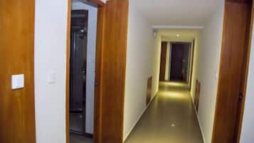 Un pasillo con puertas de madera, una lámpara en el techo y piso de baldosas.