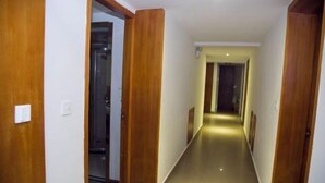A hallway with wooden doors and a glass elevator. - Jinyuan Motel (Yueqing)