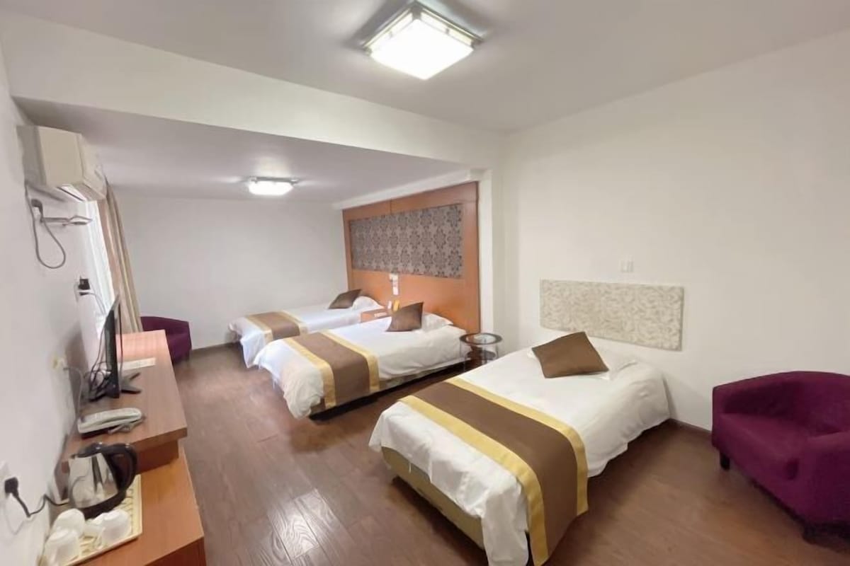 A hotel room with two beds, a desk, a chair, and a small table.