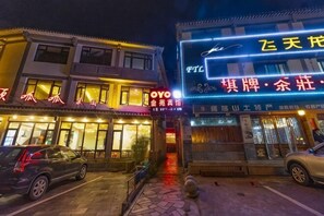 A building with illuminated signage, a storefront with a red awning, and a parked car in front. - Jinyuan Motel (Yueqing)