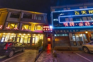 A building with illuminated signage, a storefront, and a parked car.