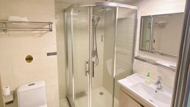 Un bagno moderno con doccia vetrata, un lavabo bianco con specchio sopra e un water a sinistra.