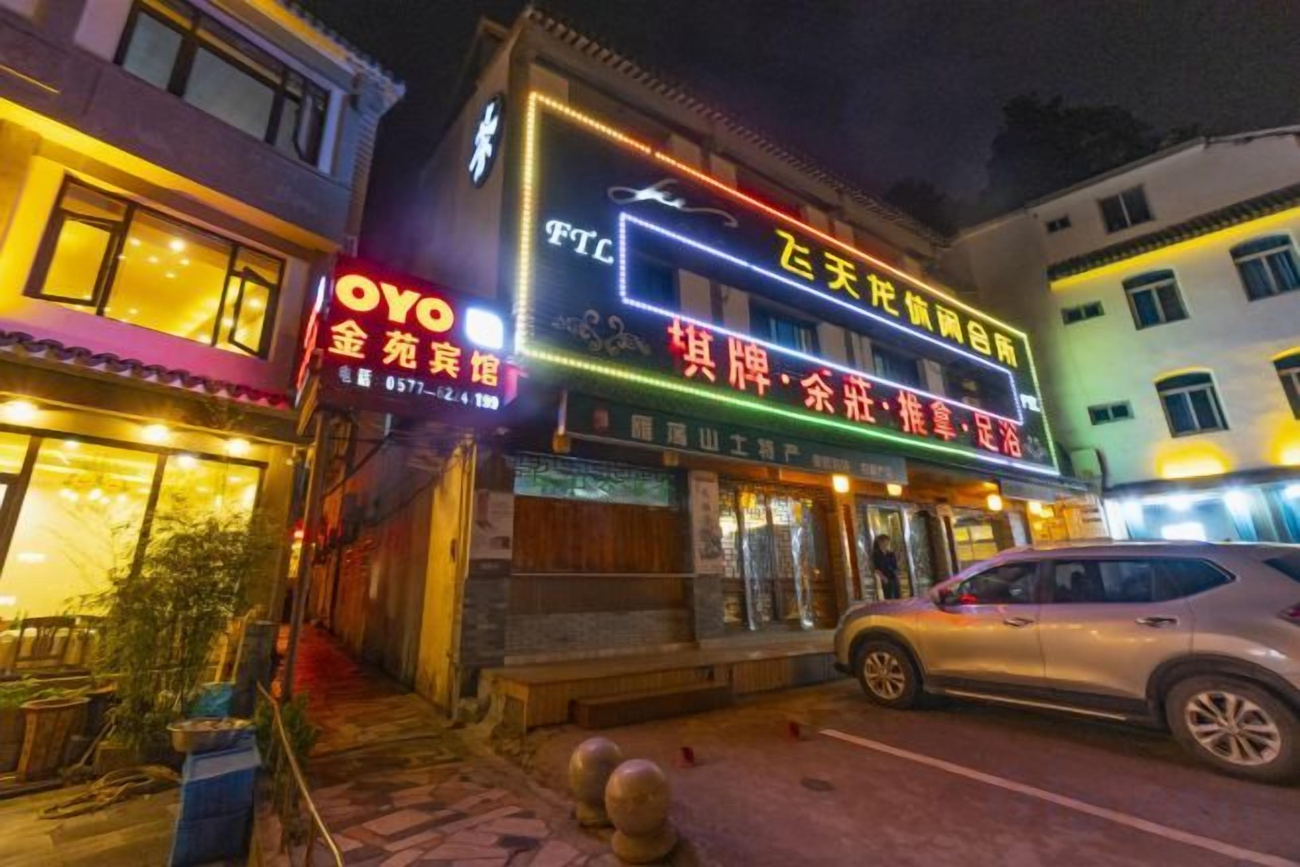 Un bâtiment avec une enseigne lumineuse, une vitrine et une voiture garée.