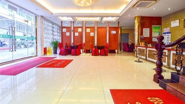 A hotel lobby with a reception desk, red chairs, a staircase, and a large window. - Jinyuan Motel (Yueqing)