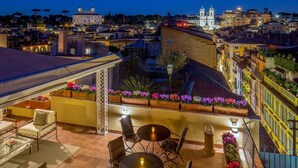 A rooftop terrace with outdoor seating, a view of the cityscape, and a building with a bell tower. - The Inn at the Spanish Steps Exclusive Collection - Condotti Luxury Suites (Rome)