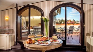 A dining area with a round table set for a meal, two large arched windows, and a view of the outdoor patio. - The Inn at the Spanish Steps Exclusive Collection - Condotti Luxury Suites (Rome)