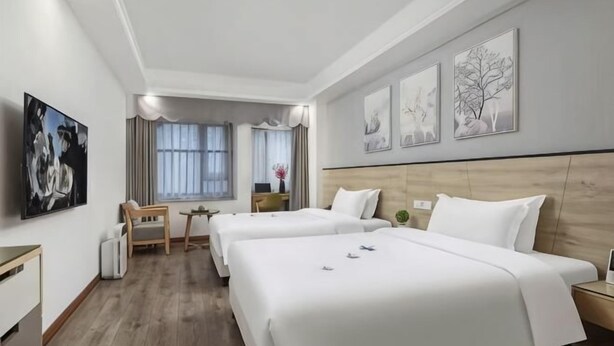 A hotel room with two beds, a desk, a chair, a window with curtains, and artwork on the walls. - Xiying Hotel (Ranjiaba Subway Station) (Chongqing)