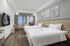 Hotellihuone, jossa on kaksi sänkyä, työpöytä, tuoli, ikkuna verhoilla ja taideteoksia seinillä.