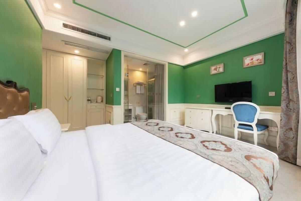 A hotel room with a bed, a desk, a chair, a television, and a wardrobe.
