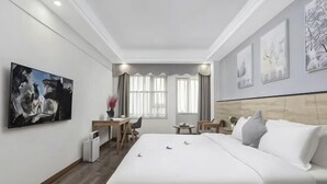 A hotel room with a large bed, a desk, a chair, and a small table. - Xiying Hotel (Ranjiaba Subway Station) (Chongqing)