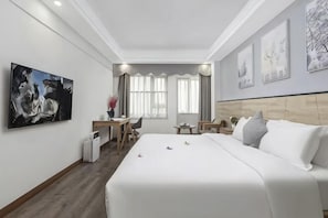 Hotellihuone, jossa on suuri sänky, työpöytä, tuoli ja pieni pöytä.