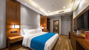 A hotel room with a large bed, wooden headboard, bedside table, and a TV on a wooden cabinet. - Xiying Hotel (Ranjiaba Subway Station) (Chongqing)