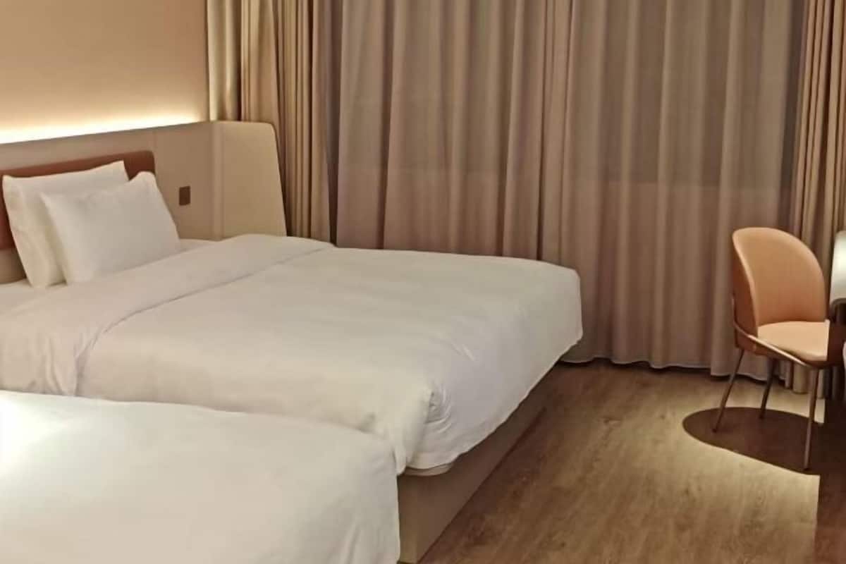 A hotel room with a large bed, a chair, and a curtain.