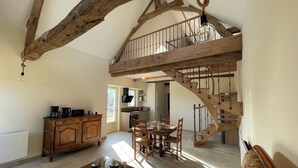 A spacious living area with a wooden staircase, a dining table set with tea service, and a kitchen in the background. - Tourangelles Stables (Bréhémont)