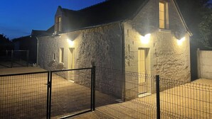 Een gebouw van steen met een omheind binnenterrein, verlicht door buitenverlichting.