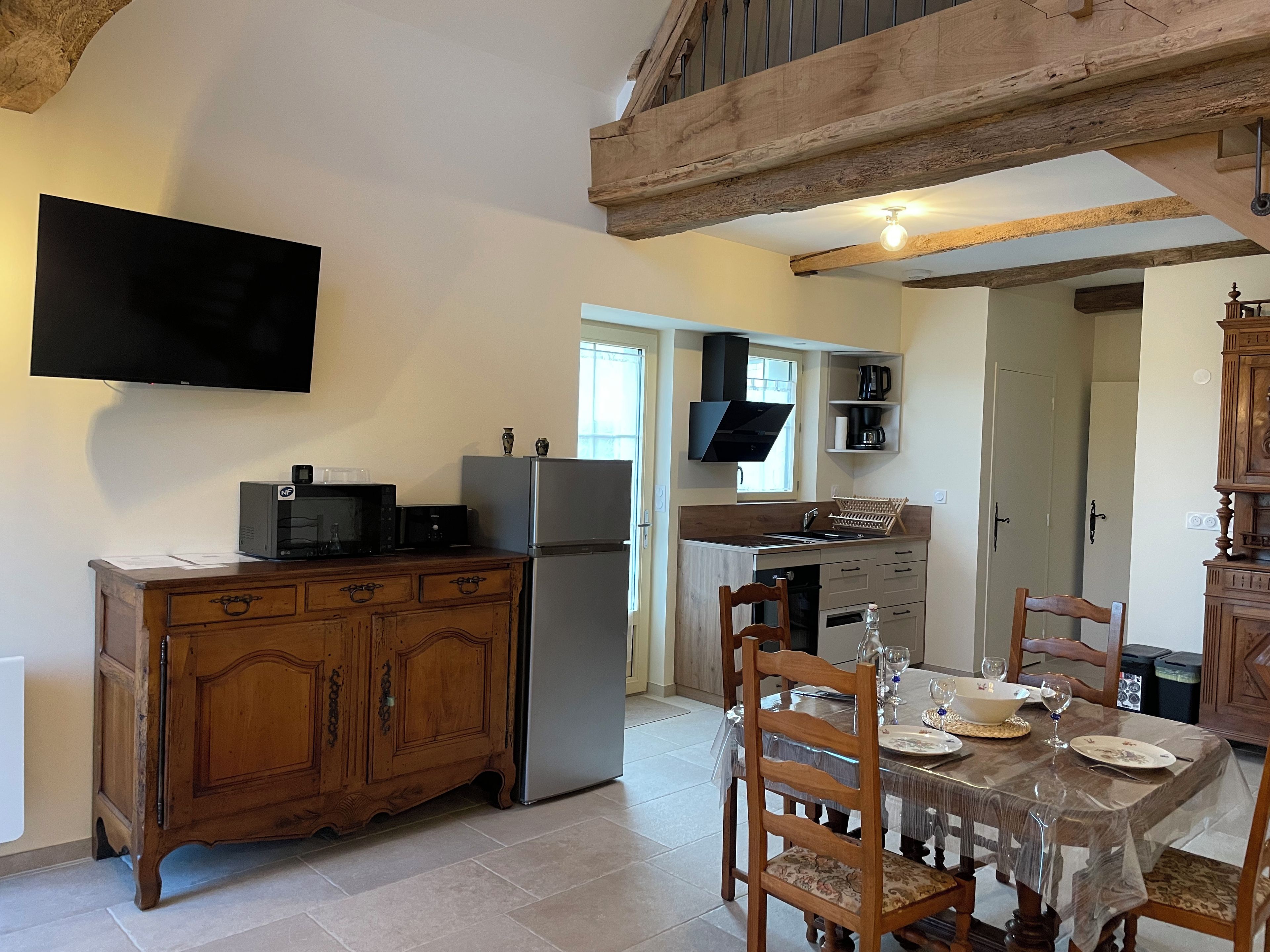 A compact kitchen with a built-in microwave, refrigerator, and a flat-screen TV mounted on the wall.