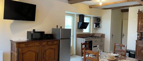 A compact kitchen with a built-in microwave, refrigerator, and a flat-screen TV mounted on the wall.