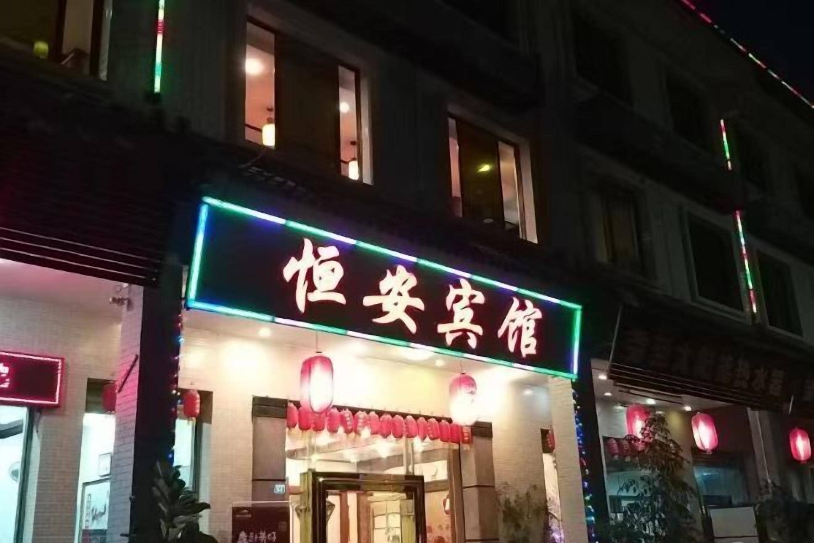A hotel with a neon sign, a visible entrance, and traditional red lanterns.