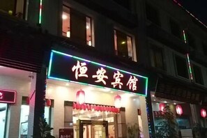 Un hotel con un letrero de neón, una entrada visible y faroles rojos tradicionales.