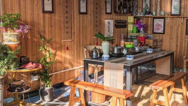 A wooden interior with a central table, benches, and various items on shelves. - Yanyang Heng'an Hotel (Meizhou)