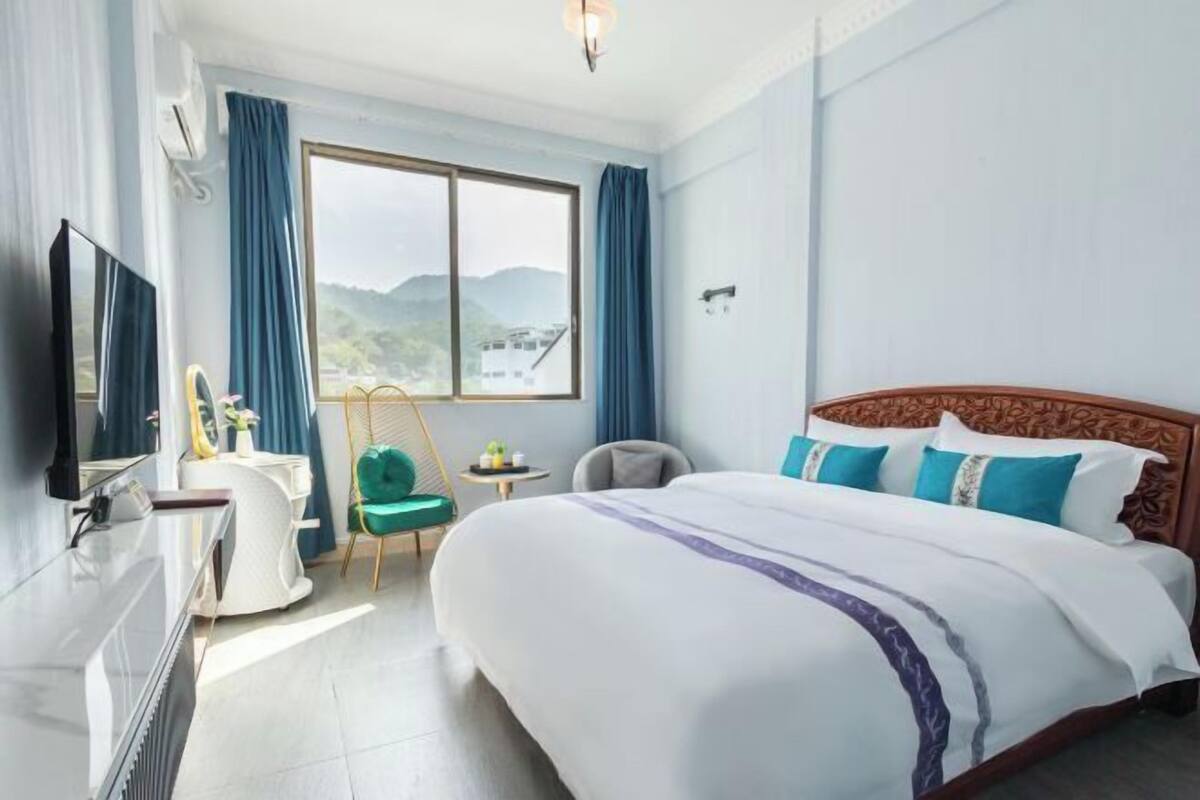 A hotel room with a large bed, a TV, a desk, and a chair.