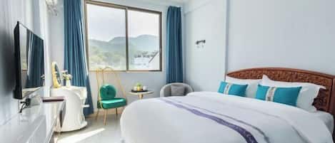 A hotel room with a large bed, a TV, a desk, and a chair.