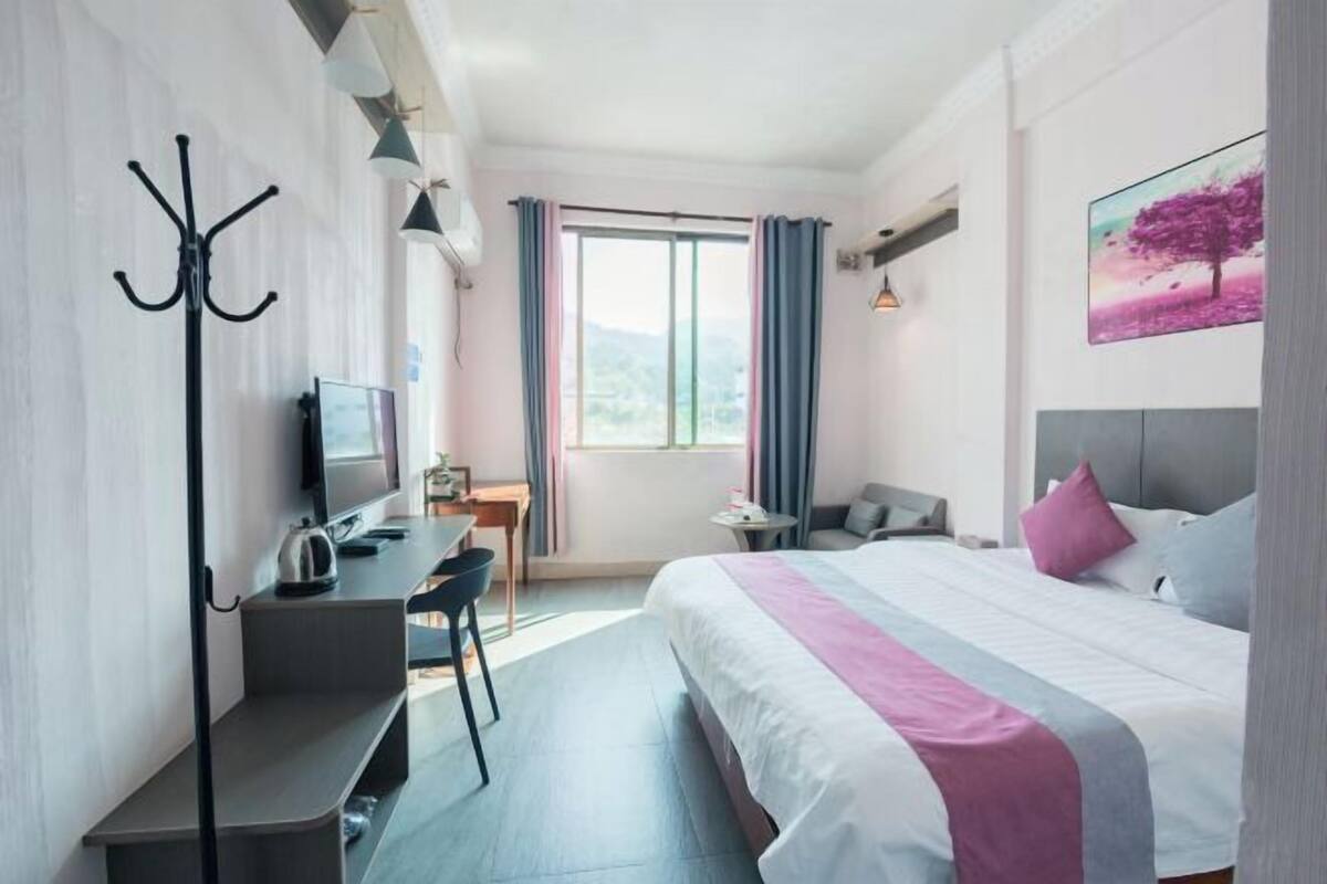 A modern hotel room with a bed, desk, chair, and a television.
