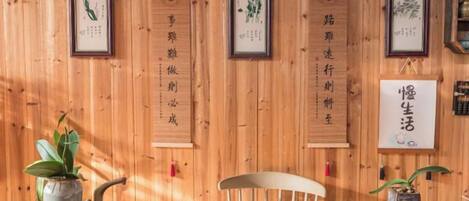 A wooden interior with a table, chairs, and framed calligraphy on the wall.