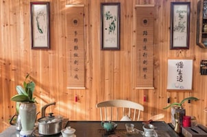 Un interior de madera con una mesa, sillas y caligrafía enmarcada en la pared.