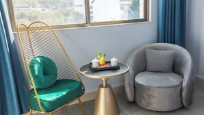 A room with a green chair, a grey armchair, a small round table with a tray, and a window with curtains. - Yanyang Heng'an Hotel (Meizhou)