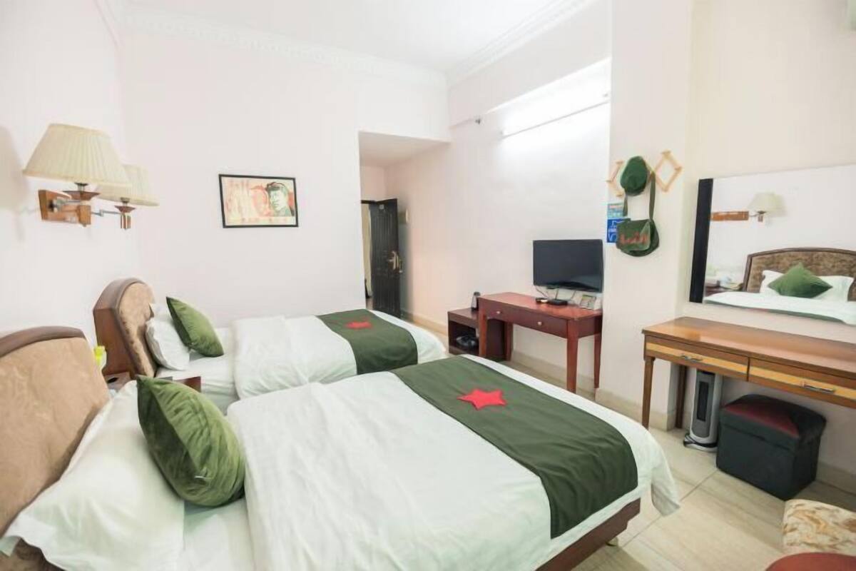 A hotel room with two beds, a desk, a chair, a TV, and a mirror.