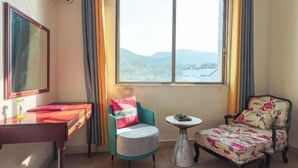 A room with a desk, two chairs, a small round table, and a large window with curtains. - Yanyang Heng'an Hotel (Meizhou)