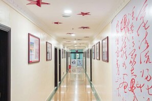 Un pasillo con cuadros en las paredes, una pared grande roja con escritura, y una puerta al final.