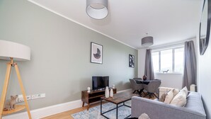A modern living room with a sofa, coffee table, TV, and artwork on the wall. - The Hackney Apartment (London)