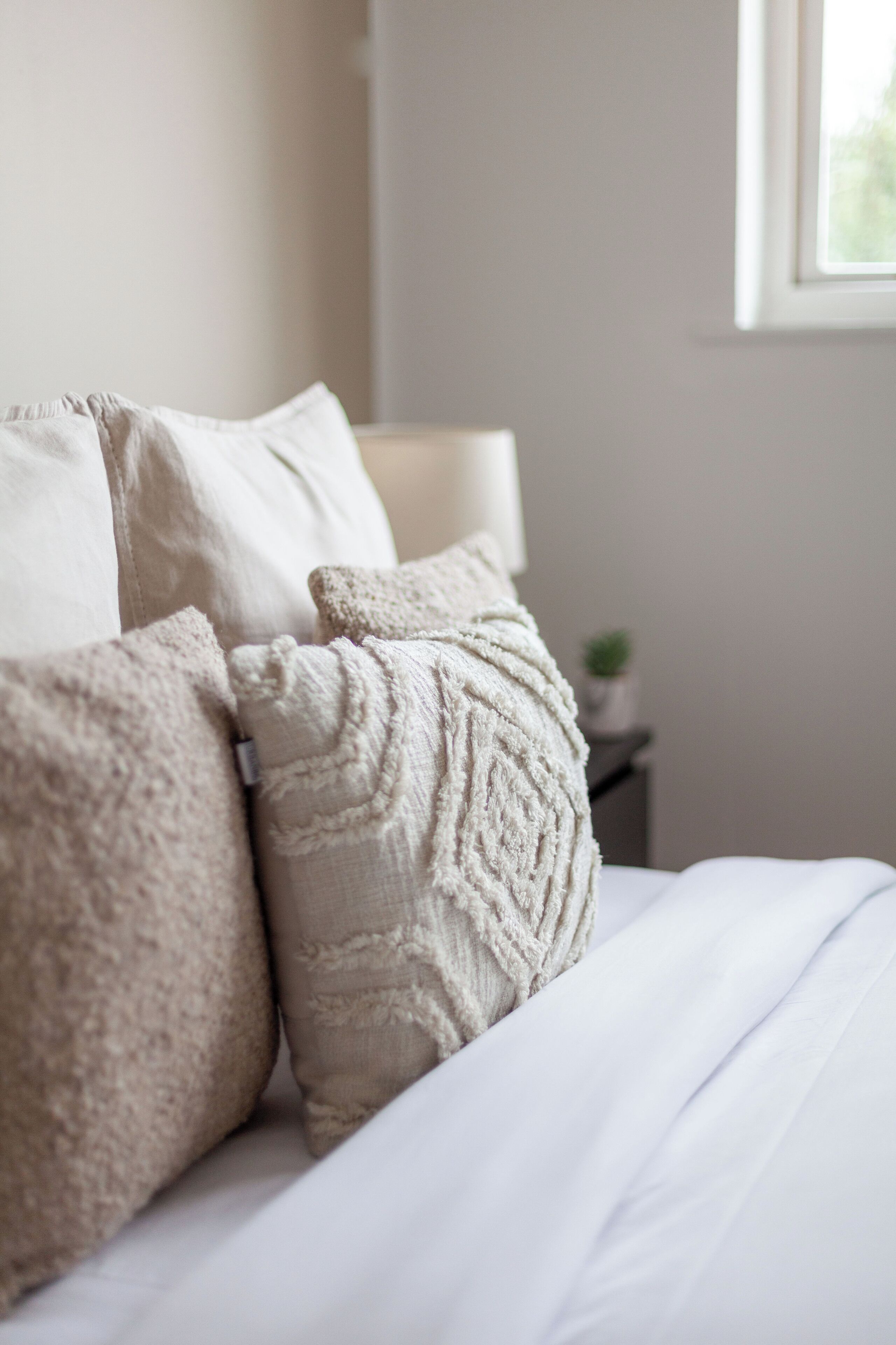 Un lit avec une literie blanche et des oreillers à texture.